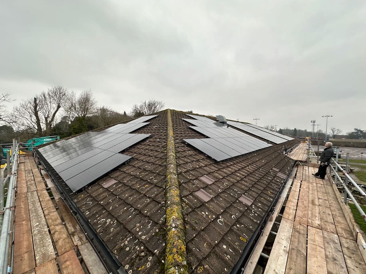 One hundred solar panels across the hipped roof of a rugby clubhouse, scaffolded all the way round