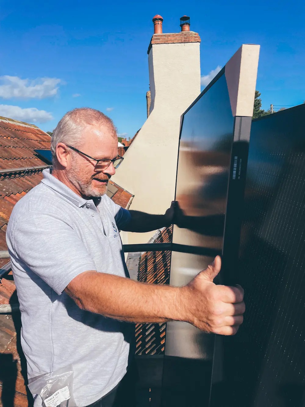 Chris carrying an all-black panel across the scaffold towards the roof