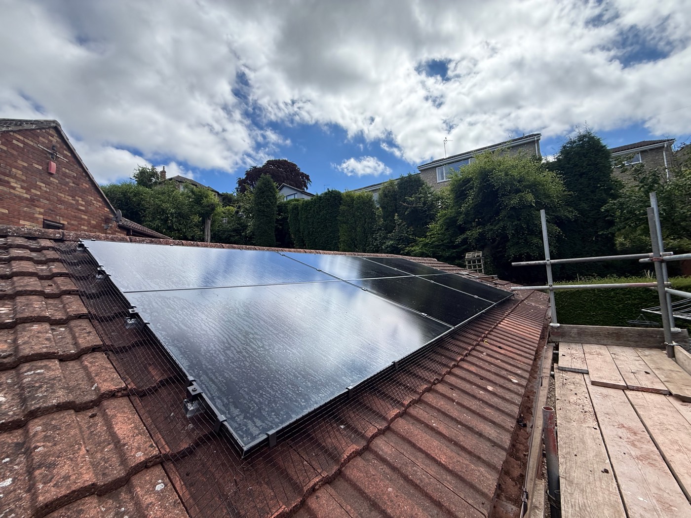 The finished south-west group of all-black panels on a tiled roof with bird protection mesh fitted at the edges