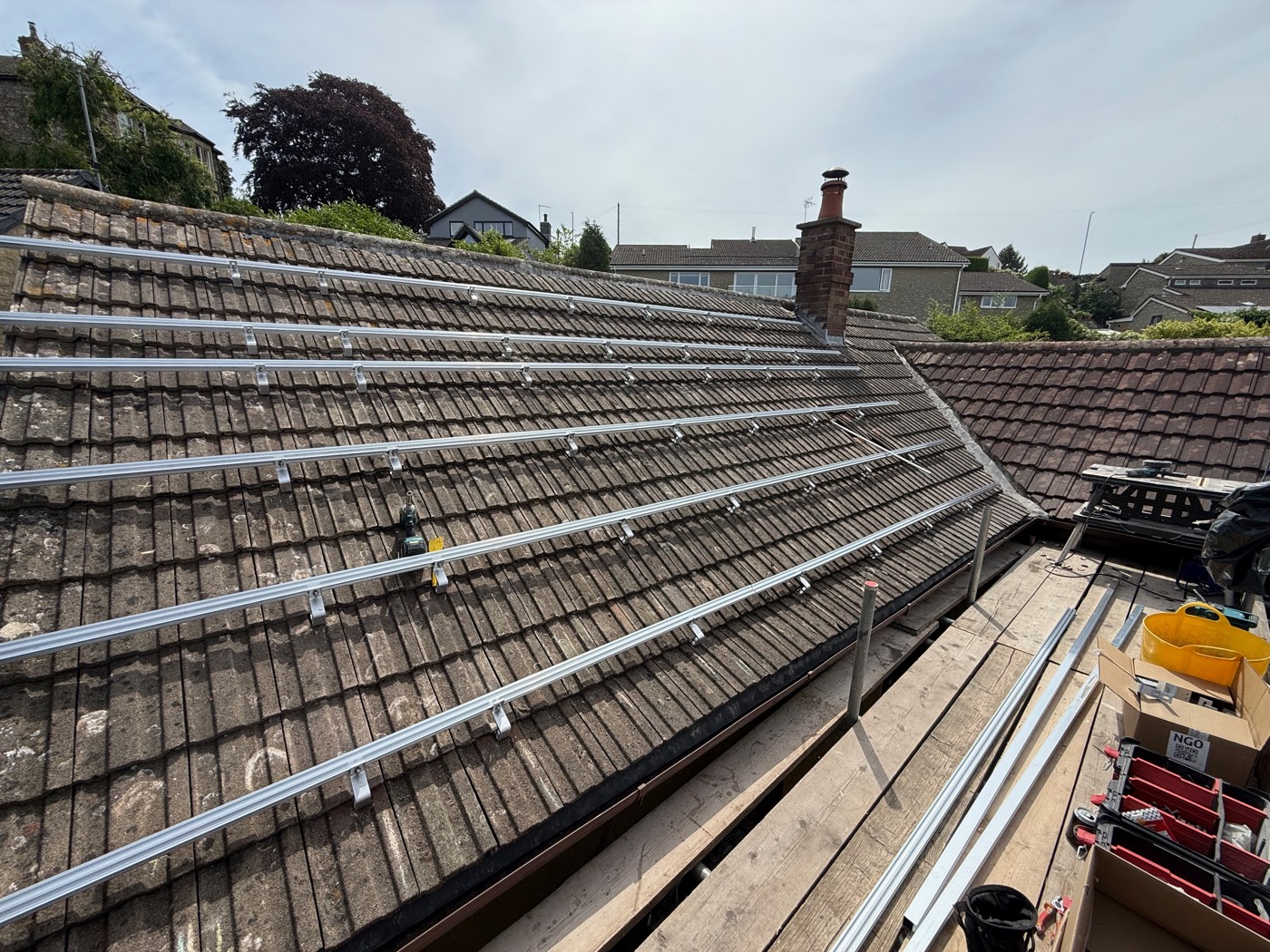 Renusol mounting rails fixed across the tiles before the panels go on, with the scaffold alongside