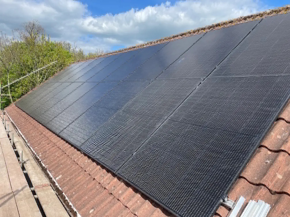 Twenty all-black solar panels laid across a south-west facing tiled roof under a blue sky