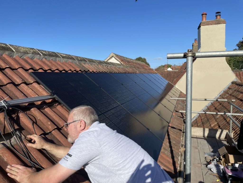 One of the team checking over a solar array at the roof edge