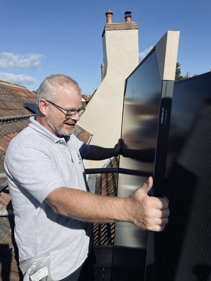 A Sunny's installer carrying a solar panel across a roof