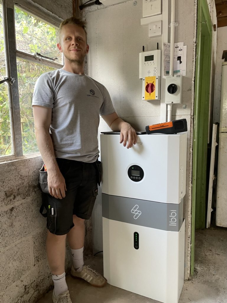 One of the team commissioning a retrofit battery beside an existing solar setup
